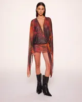 Minivestido cruzado con estampado animal print en tonos naranja, marrón y negro. Tiene escote en V pronunciado, mangas largas acampanadas y falda ajustada.