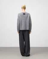 Cárdigan de lana en color gris melange con diseño de punto calado. Presenta cuello en V, mangas largas con terminación en canalé y cierre frontal mediante botones al tono.