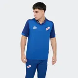 Remera polo de fútbol Umbro del Club Nacional de Football, color azul con cuello en V y detalles en rojo y blanco.