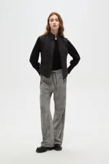 Chaleco negro con diseño capitoneado, cierre frontal con botones a presión y cuello alto.