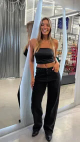 Pantalón de jean negro de calce wide leg y tiro medio, con detalle de estrellas brillantes en los bolsillos traseros.