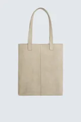 Bolso tipo shopper color beige, fabricado en piel con acabado serraje. Tiene dos asas de mano y un compartimento principal sin cierre. El interior cuenta con un bolsillo con cierre mediante cremallera.