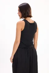 Top halter negro ajustado al cuerpo, con aplicaciones de tachas metálicas plateadas distribuidas por toda la prenda.