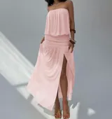 Vestido largo color beige, sin tirantes, con escote recto y detalle fruncido en la cintura. La falda es fluida y tiene una abertura lateral.