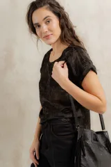 Remera de manga corta con acabado brillante y textura sutil, de corte holgado y cuello redondo. Presenta un diseño versátil y elegante en color negro con destellos dorados.