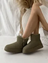 Botas tipo pantubota color verde militar, con interior forrado en piel sintética, suela de goma al tono y cierre lateral funcional.