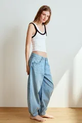 Jeans de tiro medio y diseño balloon, color azul denim con efecto lavado, cinco bolsillos, cierre frontal con cremallera y botón metálico, y bajos acabados en puño.