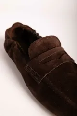 Mocasines de gamuza color marrón con diseño clásico de antifaz y costuras reforzadas en la puntera.