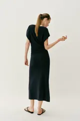 Vestido largo de punto color negro, con cuello barco, manga corta y frunces laterales en la cintura.