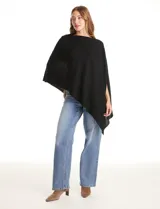 Poncho tejido de punto con diseño asimétrico y aberturas laterales para los brazos.