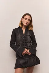 Camisa de jean negro con diseño trenzado, cuello clásico, cierre frontal con cordones y mangas largas con puños anchos.