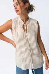 Blusa blanca sin mangas con cuello mao y pliegues verticales.