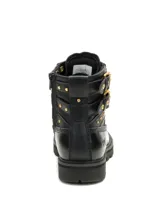Bota de cuero negro con diseño robusto, cordones frontales y cierre lateral. Presenta detalles de tachuelas metálicas doradas, dos hebillas laterales decorativas y el logo de la marca en amarillo en la lengüeta y grabado en el talón. Cuenta con suela de goma dentada para mayor tracción.
