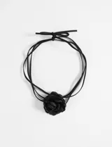 Collar tipo choker negro con diseño de flor central de tela y tiras finas ajustables mediante lazo.