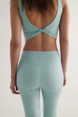 Leggings de yoga acampanados de tiro alto en color verde menta, confeccionados en tejido funcional con detalle de torsión en la cintura.