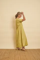Vestido tipo túnica largo de lino, color bordo, con mangas cortas, bolsillos laterales y detalle de volados en la botonera frontal.