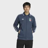 Campera deportiva Adidas de la selección de Italia, color azul con diseño retro. Presenta cuello tipo polo, cierre frontal completo, bolsillos laterales y las icónicas tres tiras de la marca en las mangas. Incluye el logo del Trifolio y el escudo de la Federación Italiana de Fútbol en el pecho.