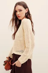 Sweater de punto calado color beige con hilos de lurex, de corte recto, manga larga y cuello redondo con terminación elástica acanalada.