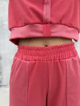 Conjunto deportivo de dos piezas en color rojo, compuesto por un buzo corto con capucha y un pantalón de jogging con cintura elástica.