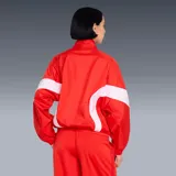 Campera Puma modelo Wardrobe Essentials, color rojo con bandas blancas en las mangas y el torso, cuello semi-alto y cierre frontal. Incorpora tecnología windCELL para protección contra el viento y cuenta con el logo de la marca bordado en el pecho.