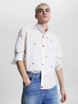 Camisa blanca de popelina de puro algodón con estampado de banderas náuticas y logos de Tommy Jeans bordados. Corte clásico, cuello abotonado, puños con botón y bajo redondeado.