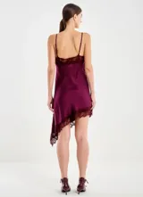Vestido corto de satén color bordó, con tirantes finos regulables y escote en V. Presenta aplicaciones de encaje en el escote y en el bajo asimétrico, con una silueta fluida y holgada.