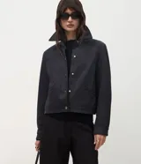 Chaqueta de corte recto confeccionada en suede sintético, con cuello estilo camisa, cierre frontal con botones metálicos, mangas largas y bolsillos embutidos.