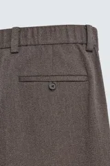Pantalón de traje wide fit color marrón oscuro con textura, pinzas frontales, bolsillos laterales y cierre con cremallera y botón.