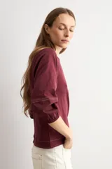 Remera bordó de manga larga con detalles en popelina en las mangas y costuras visibles en contraste.
