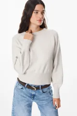 Sweater de punto color crudo con cuello redondo, mangas largas con puños anchos acanalados y cintura también acanalada. Presenta un diseño de silueta holgada y mangas con volumen.