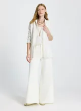 Saco largo tejido color blanco con textura en relieve, corte recto, cuello semi alto, mangas largas y ribete de flecos en el dobladillo, los puños y el cuello.