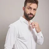 Camisa de vestir negra de manga larga, confeccionada en tejido técnico elástico y libre de arrugas, con cuello clásico y cierre frontal de botones.