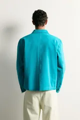 Cazadora relaxed fit de denim de algodón color turquesa, con cuello solapa, manga larga con puño abotonado, bolsillos frontales con solapa y cierre de botones metálicos.