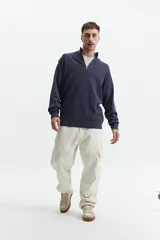 Buzo de tejido de punto color azul marino, con cuello elevado y cierre parcial frontal. Presenta un pequeño logo bordado en el pecho.