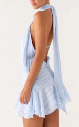 Vestido corto celeste con diseño halter fruncido en el cuello, cuerpo holgado con textura a rayas sutiles, cintura estructurada con fruncidos horizontales y falda con volados.