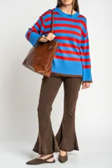 Sweater de punto con diseño de rayas horizontales en azul y rojo, cuello redondo y puños con terminación en color marrón.