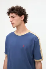 Remera de manga corta azul con cuello redondo, puños y bandas en los hombros en color tostado. Presenta un pequeño bordado rojo en el pecho y está confeccionada en suave jersey de algodón con calce clásico.