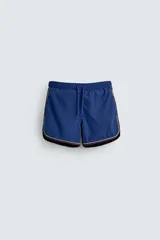 Short de baño azul con cintura elástica ajustable con cordón, bolsillos laterales y ribetes en contraste en los bordes.