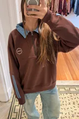 Buzo de algodón color marrón con diseño estilo rugby. Presenta cuello tipo camisa en denim celeste, cierre frontal parcial, logo bordado en el pecho y tiras laterales en las mangas en contraste.