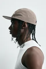 Gorra de seis paneles color marrón topo con visera plana y ojales bordados. Presenta bordado frontal en blanco con el texto "Alternative Lifestyle" y "Trastevere, Rome.".