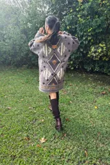 Vestido tipo sweater oversize de lana, tejido a mano con técnica de intarsia y detalles bordados. Presenta un diseño geométrico de rombos en tonos azul marino, beige y verde, con cuello redondo y mangas largas.