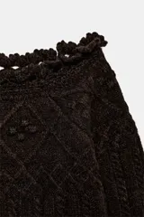 Jersey de punto color marrón oscuro con diseño de ochos y rombos, escote tipo barco con borde decorativo en ondas y manga larga.