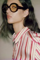 Camisa de cuello solapa con estampado de rayas verticales en tonos rojos, rosas y blancos. Presenta cierre frontal con botones y mangas por debajo del codo con terminación en vuelta.