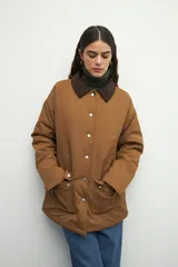 Campera color verde militar con cuello de pana marrón, bolsillos con solapa y botones metálicos. Interior forrado con tela satinada capitoneada.