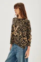 Sweater de punto con cuello redondo y manga larga, presentando un estampado tipo ikat o animal print abstracto en tonos marrón claro y negro/gris oscuro.