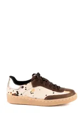 Zapatillas urbanas de diseño combinado, con paneles de cuero vacuno con textura de pelo animal print en tonos beige y marrón, detalles en cuero marrón liso y refuerzo metalizado en el talón. Cuenta con suela de goma color suela y cierre con cordones.