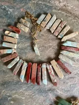 Collar corto elaborado artesanalmente con piedras naturales de jaspe en tonos turquesa, terracota y beige, con cierre y cadena de extensión dorados.