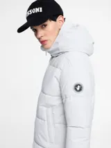 Parka larga acolchada color negro con capucha, cierre frontal con cremallera y bolsillos laterales.