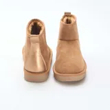 Botas cortas de estilo casual en color marrón, confeccionadas en ante sintético con interior forrado en piel sintética para mayor calidez. Presentan una suela plana de goma con relieve dentado y un tirador en la parte trasera.