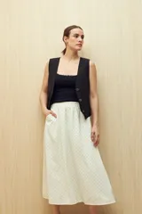 Falda midi color blanco con estampado de lunares negros.